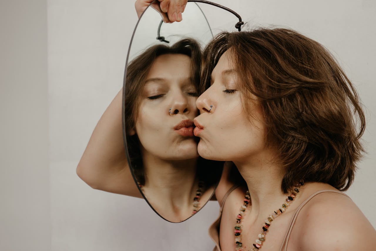 A woman embraces her reflection in an oval mirror, symbolizing self-love and acceptance.
