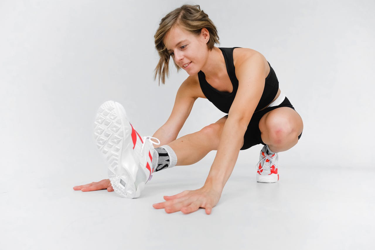Woman in athletic wear stretching indoors, focused on fitness and exercise.