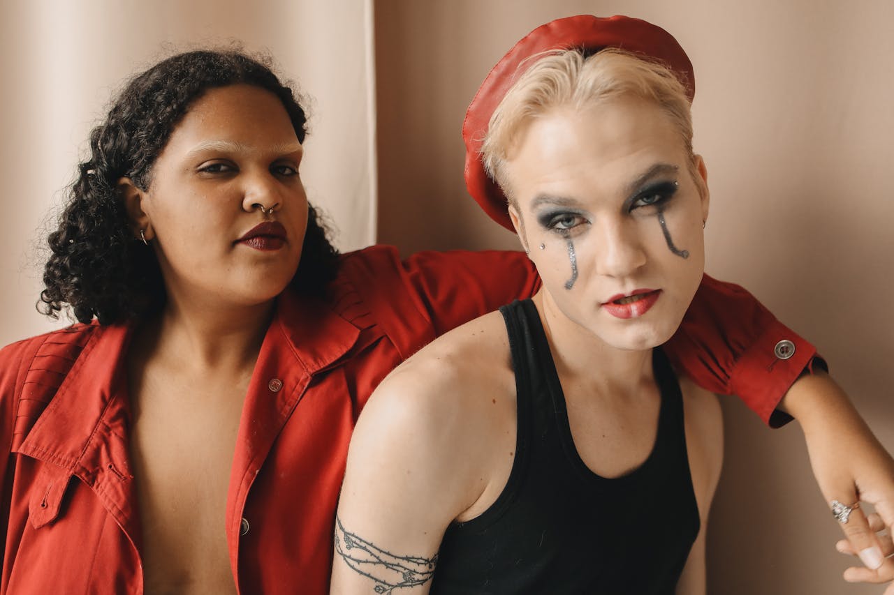 A striking portrait of two stylish friends with bold makeup, showcasing diversity and fashion in a studio setting.